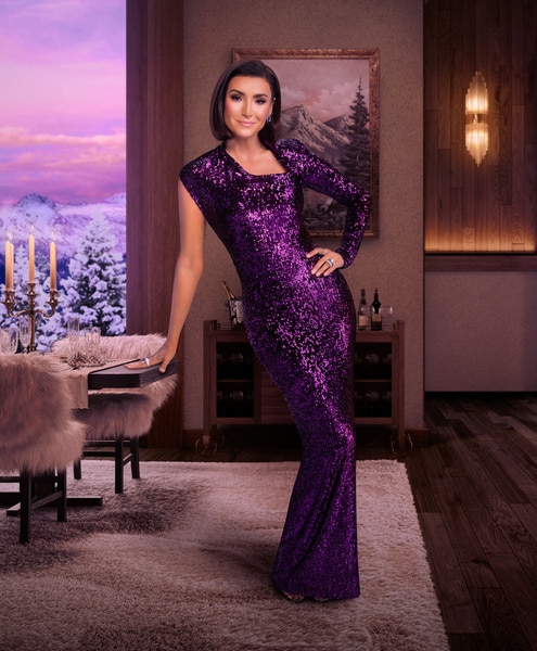 Bronwyn Newport wearing a purple gown in a wooded living room overlooking a snowy mountain